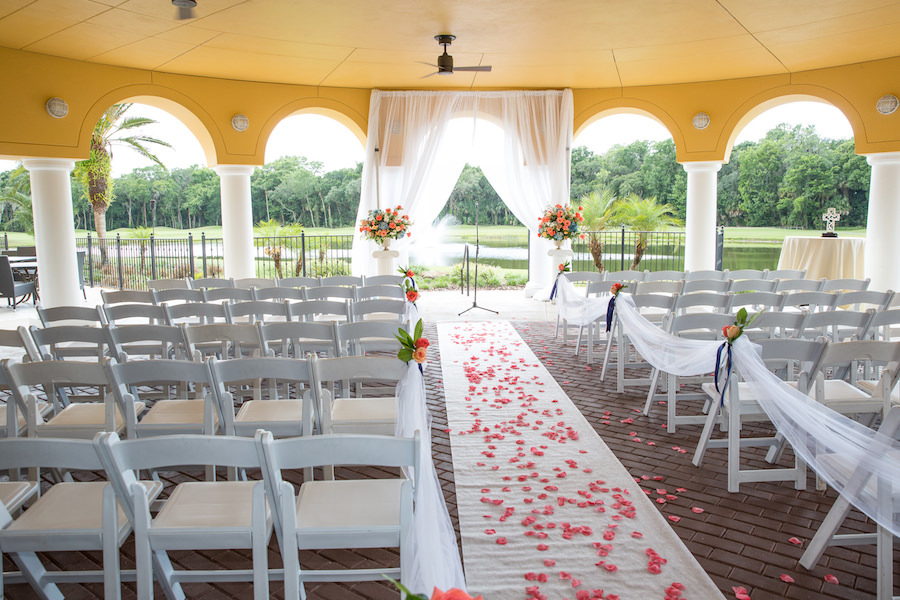 Outdoor, Wedding Ceremony with White Garden chairs, Flower Petal Aisle, White Runner and Coral and Pink Wedding Flowers with Draping at Tampa Wedding Venue Tampa Palms Golf and Country Club