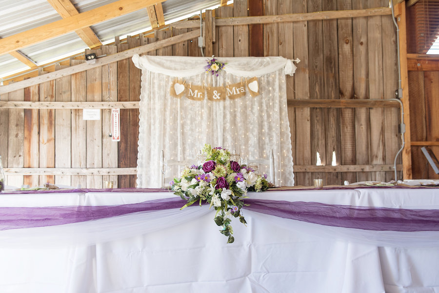 Plant City Barn Wedding Reception Decor with Mr and Mrs Burlap Sign and White and Purple Floral Decor with Purple Table Sash