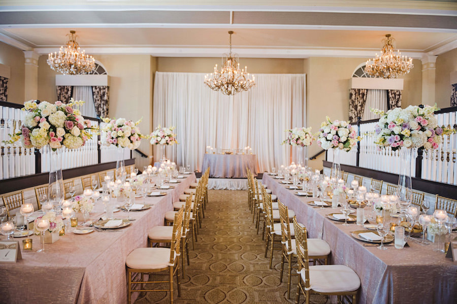 Long Feasting Tables with Candles and Tall Ivory, Pink and Purple Centerpieces on Lilac Specialty Linens with Gold Chiavari Chairs at Tampa Wedding Reception Venue Loews Don CeSar Hotel | Photography by Tampa Wedding Photographer Marc Edwards Photographs