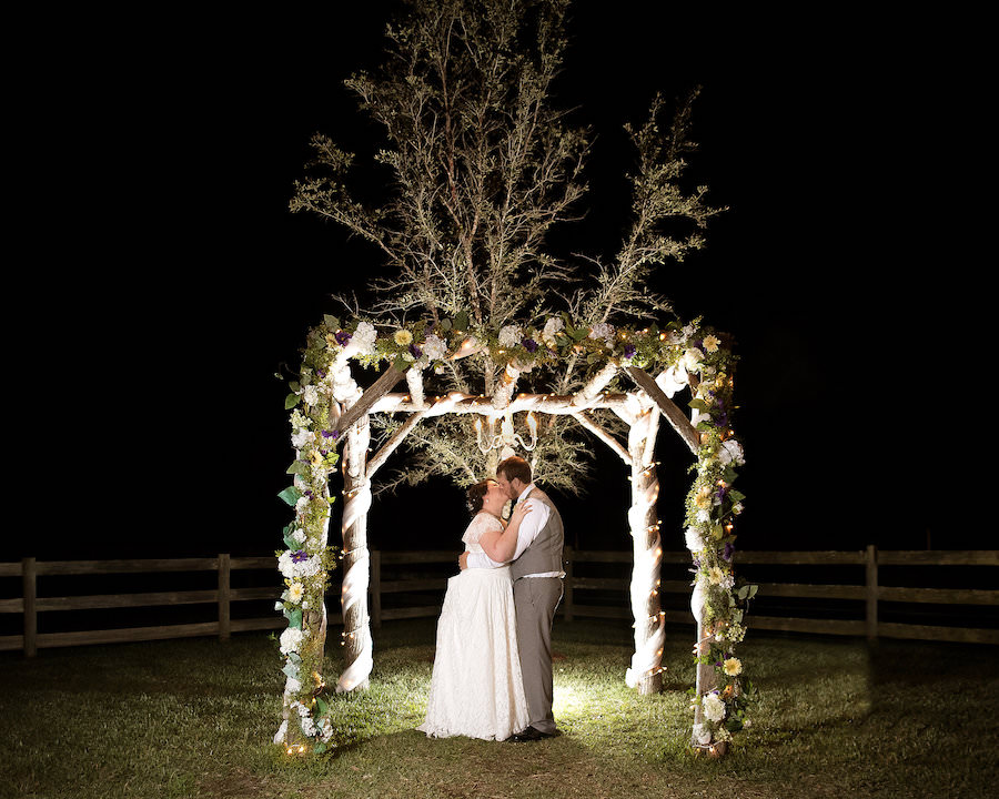 Nighttime, Outdoor, Plant City Bride and Groom Wedding Portrait Under Floral Ceremony Altar