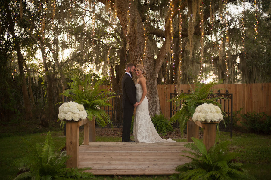 Outdoor, Bride and Groom Wedding Portrait Under Mossy Oak Tree with Twinkle Lights on Love Lock Bridge at Sarasota Wedding Venue Bakers Ranch