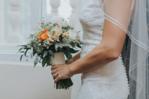 Bridal Wedding Portrait in Lace, Ivory, Allure Wedding Dress and Orange, Peach, and White Floral Bridal Bouquet with Greenery