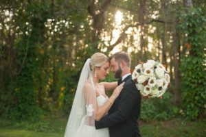 Outdoor Bride and Groom Wedding Portrait in the Woods | Groom in Black Tuxedo and Bride in Ivory Strapless Wedding Dress with Cathedral Veil and Large Ivory and Brown Floral Wedding Bouquet | Fall Wedding Inspiration