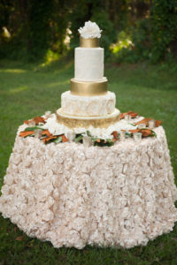 Four Tier Gold and Ivory Round Wedding Cake with Hand Painted Sugar Flowers on Satin Specialty Linen with Textured Rosettes