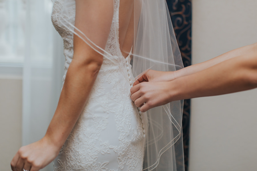 Bride Getting Dressed in Ivory, Lace, Allure Wedding Dress