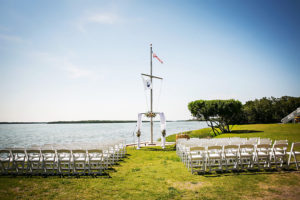 Waterfront St. Petersburg Wedding Ceremony with Draped Arch and Pastel Peach Flowers and White Folding Garden Chairs | St. Petersburg Wedding Venue Tampa Bay Watch