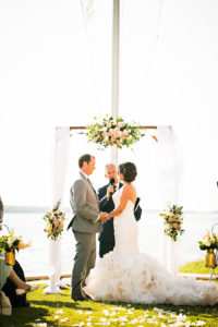 Waterfront St. Petersburg Wedding Ceremony with Draped Arch and Pastel Peach Flowers and White Folding Garden Chairs | St. Petersburg Wedding Venue Tampa Bay Watch | Photographer Limelight Photography