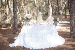 Winter Inspired Outdoor Wedding Reception Cake Table with Custom Ivory Linens and Blush and Ivory Floral Accents