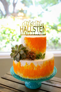 Bright Orange Two Tier Wedding Cake on Vintage Milk Glass Cake Stand with Succulent Accent