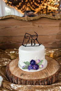 Rustic White Round Wedding Cake With Purple Fondant Flowers On A Wooden Slice and Wine/Beer Glass Cake Topper | Tampa Wedding Cake Baker Alessi Bakery| Photography by Caroline and Evan Photography
