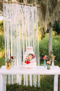 Four Tiered Naked Boho Chic Wedding Cake with Floral Accent with Macrame Backdrop