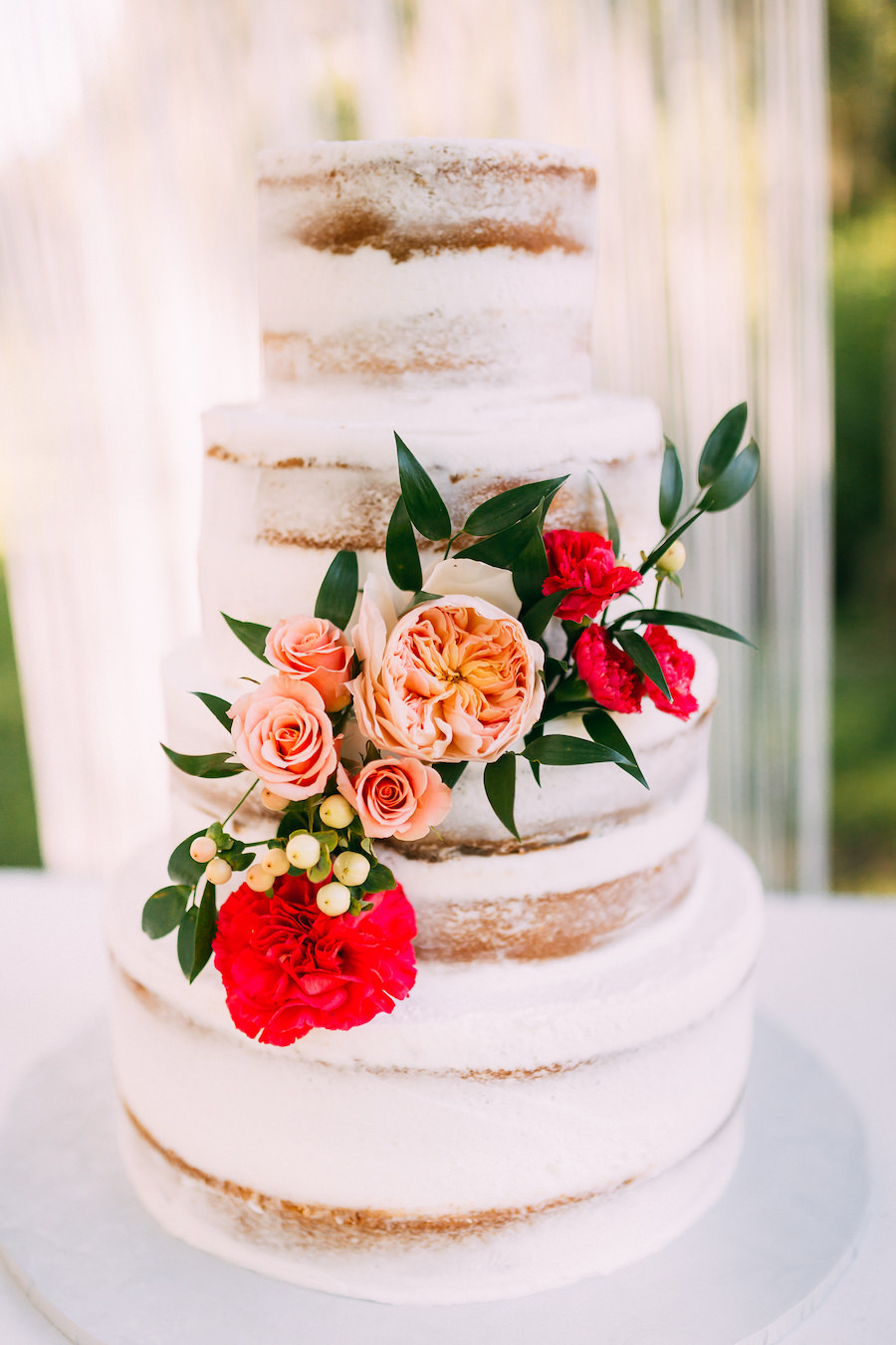 Four Tiered Naked Boho Chic Wedding Cake with Floral Accent with Macrame Backdrop