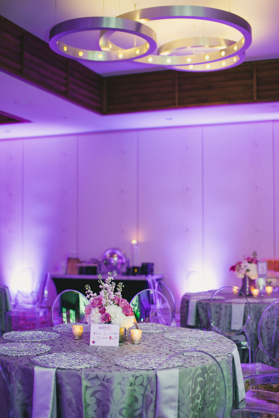 Silver Reception Decor with Pink and White Wedding Centerpieces, Purple Uplighting and Ghost Chairs | Linens by Over the Top Rental Linens | Chargers by Signature Event Rentals | Lighting by Gabro Event Services | Roohi Photography