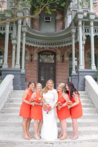 Bridal Wedding Portrait in Long Sleeve Lace Wedding Dress with Bridesmaids in Bright Orange Tea Length Dresses and Vibrant Pink, Orange and Green Wedding Bouquets