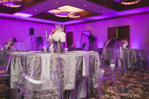 Silver Reception Decor with Pink and White Wedding Centerpieces, Purple Uplighting and Ghost Chairs | Linens by Over the Top Rental Linens | Chargers by Signature Event Rentals | Lighting by Gabro Event Services | Roohi Photography