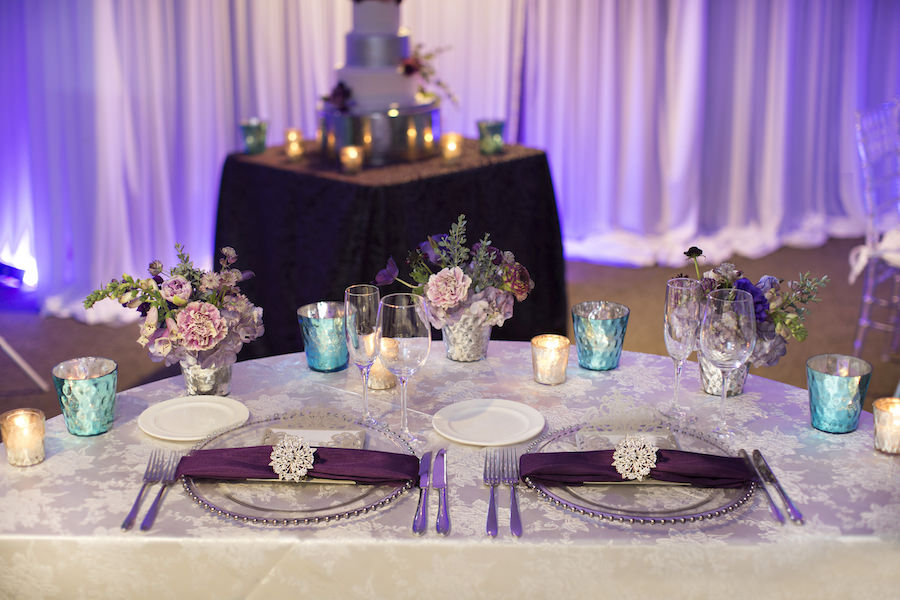 Beaded Glass Charger with Silver Wedding Menu and Purple Napkin with Rhinestone Holder | Purple and Deep Red Centerpieces with Candles on Ivory Linens | Sweetheart Table Wedding Reception Ideas & Inspiration | Special Moments Event Planning | Connie Duglin Linens