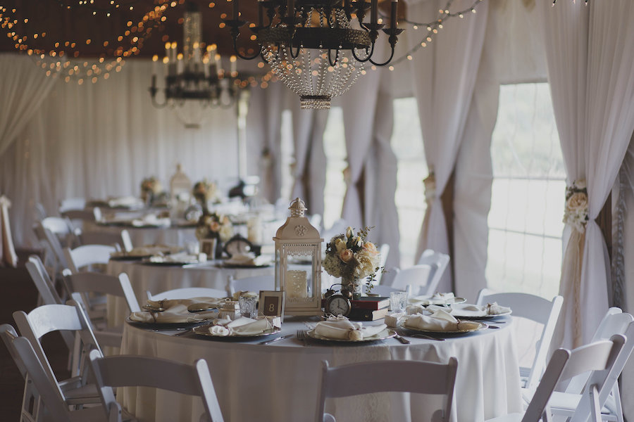 Rustic Wedding Reception Table Decor with Peach and Ivory Floral Centerpieces, Vintage Books, and White Lanterns | Tampa Bay Wedding Venue Cross Creek Ranch