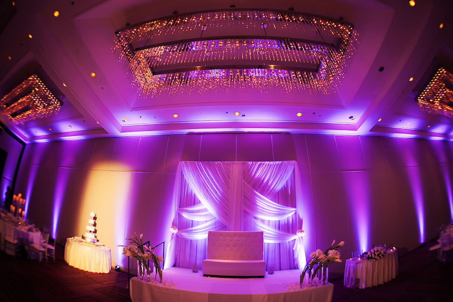 Elegant Glamorous Ballroom Wedding Reception Decor with White Drapery Backdrop, Purple Uplighting, and Ivory Floral Centerpieces | Tampa Wedding Venue Hilton Downtown