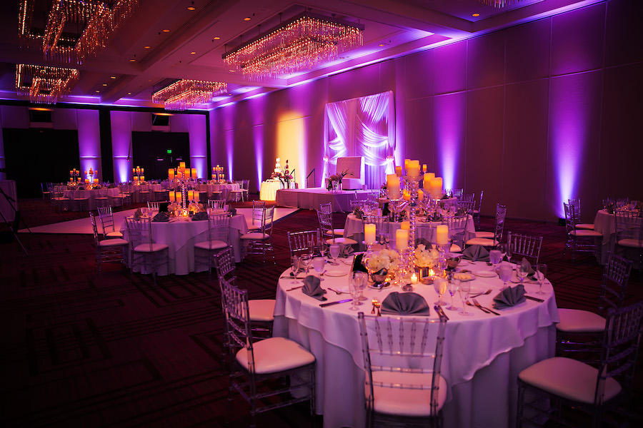 Elegant Wedding Reception Decor with White Drapery Backdrop, Purple Uplighting, and Ivory Floral Centerpieces and Candelabras and Clear Chiavari Chairs | Limelight Photography | Tampa Wedding Venue Hilton Downtown