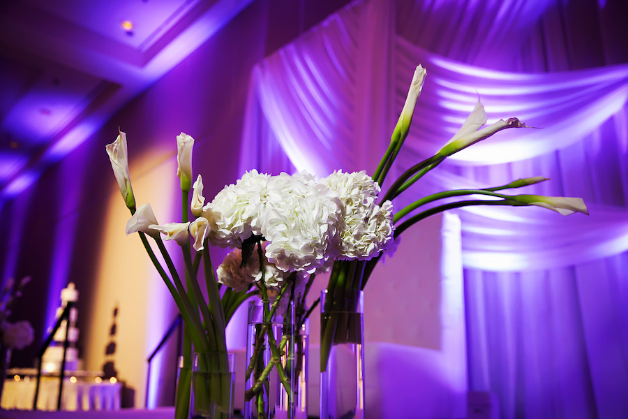 White Floral Centerpieces and Stems at Elegant Ballroom Wedding Reception with White Drapery Backdrop, Purple Uplighting | Limelight Photography | Tampa Wedding Venue Hilton Downtown