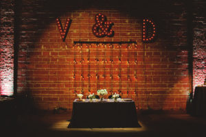 Bride and Groom Sweetheart Table with Lighted Marquee Monogram Letters, Exposed Brick and Industrial String Lights | Modern Industrial Wedding Reception Decor Inspiration | Downtown St. Petersburg Wedding Venue NOVA 535 | Special Moments Event Planning