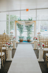 Wedding Ceremony Decor with Draped Arch, Aisle Runner and Columns with Red and White Floral Arrangements | Red and White Wedding Inspiration