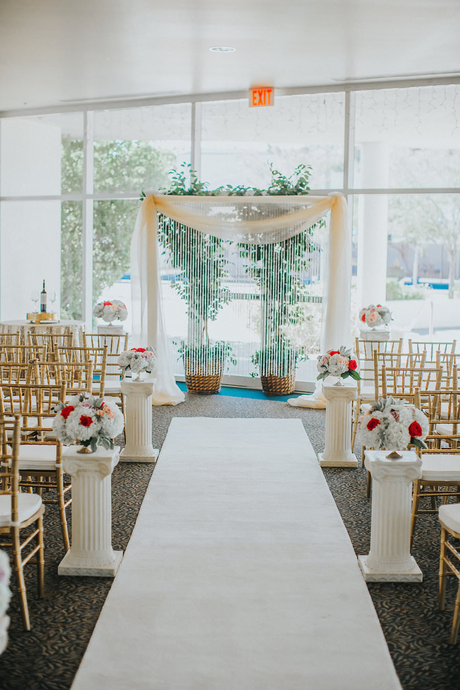 Wedding Ceremony Decor with Draped Arch, Aisle Runner and Columns with Red and White Floral Arrangements | Red and White Wedding Inspiration