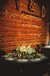 Silver and Ivory Wedding Reception Decor Centerpieces with Floating Candles, Silver Chargers and Exposed Brick Walls with Hanging String Lights | St. Petersburg Wedding Venue NOVA 535 | Signature Event Rentals | Wedding Planner Special Moments Event Planning | Iza's Flowers