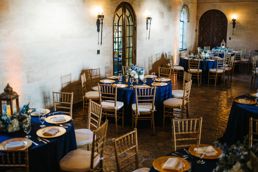 Elegant Navy Blue Wedding Reception Decor with Gold Chiavari Chairs, Blue Table Linens, Gold Chargers, and Blue and White Floral Table Centerpieces | Sarasota Wedding Florist Apple Blossoms Floral Designs | Wedding Planner Nicholle Leonard Designs