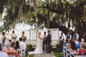 Vintage Outdoor Wedding Ceremony under Spanish Moss Tree with White Resin Folding Chairs and White French Door Arched Doorway Altar | Sarasota Rentals by Reserve Vintage Rentals | Waterfront Sarasota Wedding Venue Palmetto Riverside Bed and Breakfast
