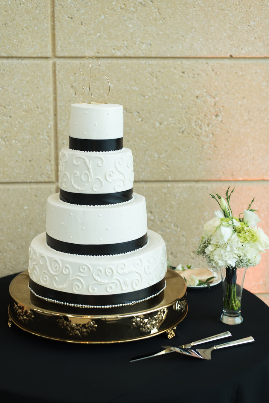Four Tier Round White Wedding Cake with Black Satin Ribbon Bands on Gold Cake Stand | Photography by Caroline and Evan Photography