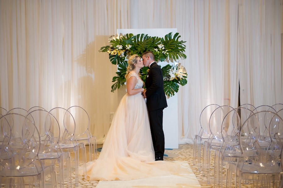 Ballroom Wedding Ceremony with Draping by Gabro Event Services, Ghost Chairs from A Chair Affair and Palm Leaf Ceremony Altar Backdrop | Hotel Wedding Venue Wyndham Grand Clearwater Beach | Andi Diamond Photography | Wedding Planner Parties a la Carte