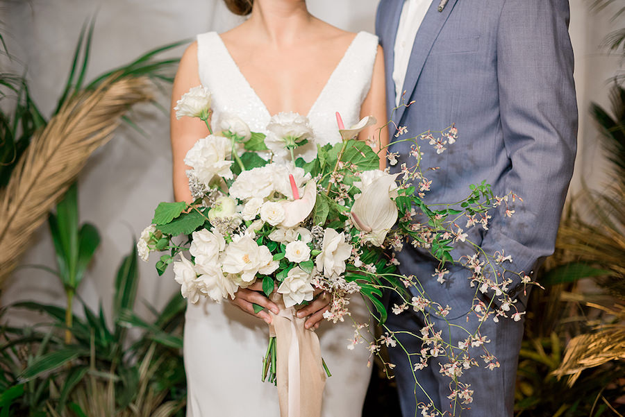 Bride in Beach Inspired Wedding Dress and Oversized Tropical Wedding Bouquet and Groom in Blue Grey Suit | Tropical Destination Beach Wedding Inspiration