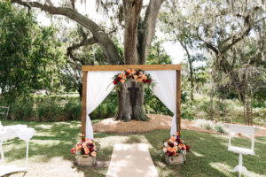 Outdoor, Rustic, Garden Wedding Ceremony with Red, Coral and Peach Floral Decor at Tampa Bay Wedding Venue Cross Creek Ranch