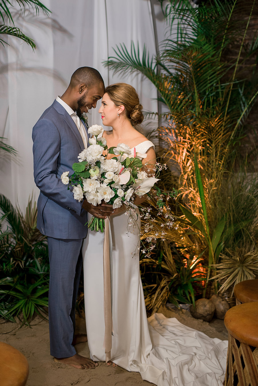 Bride in Beach Inspired Wedding Dress and Oversized Tropical Wedding Bouquet and Groom in Blue Grey Suit | Tropical Destination Beach Wedding Inspiration