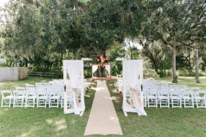 Outdoor, Rustic, Garden Wedding with Vintage Doors, White Folding Chairs and Red and Coral Floral Decor at Tampa Bay Wedding Venue Cross Creek Ranch