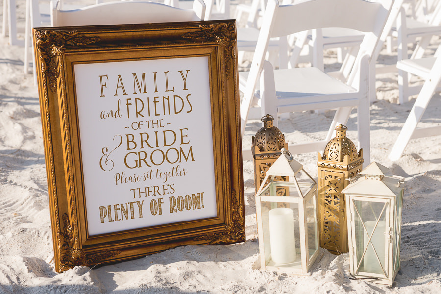 Beach Gold and White Wedding Ceremony Sign with White and Gold Lanterns | White Folding Chairs Coast to Coast Event Rental