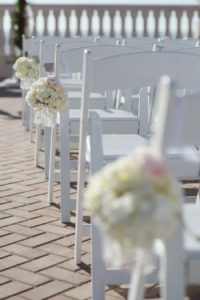 Wedding Ceremony White Resin Folding Chairs with Ivory Aisle Floral Arrangements | Clearwater Beach Wedding Planning Kimberly Hensley Events