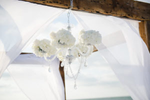 Wedding Ceremony Wooden Arch with White Drapery and Crystal Chandelier with Ivory Flowers | Clearwater Beach Wedding Planner Kimberly Hensley Events