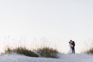 Florida Sunset beach wedding portrait | Bride and groom on sand dune with greenery | Tampa Bay Beachfront Hotel Wedding Venue Hilton Clearwater Beach