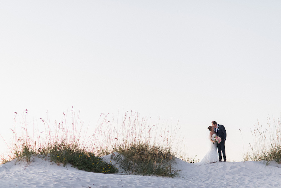 Florida Sunset beach wedding portrait | Bride and groom on sand dune with greenery | Tampa Bay Beachfront Hotel Wedding Venue Hilton Clearwater Beach