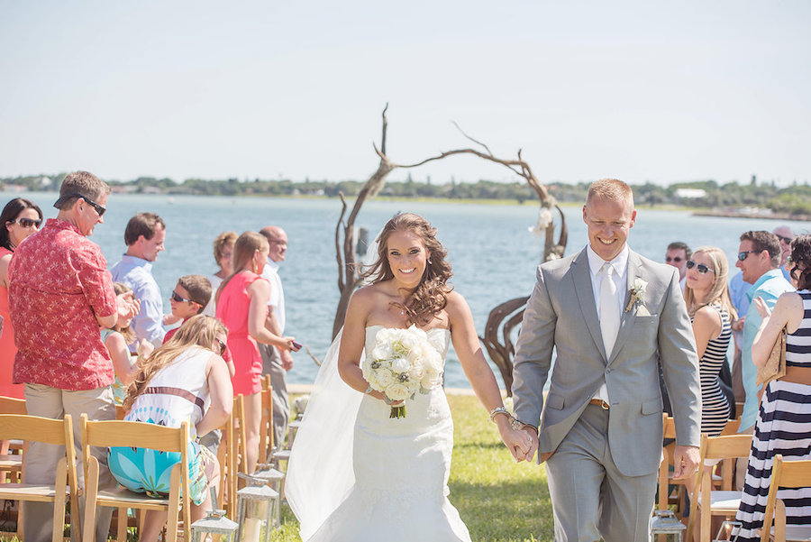 Bride and Groom Recessional Walk Down the Aisle at Waterfront Wedding Ceremony with Twisted Driftwood Wedding Arch | Driftwood Wedding Arch with White Irises and Cascading Moss | Waterfront Wedding Ceremony Decor Ideas | St Petersburg Wedding Photographer Kristen Marie Photography