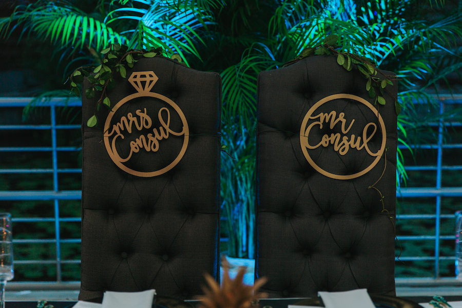 Black Tufted Wedding Sweetheart Chairs with Mr. and Mrs. Signs in Gold Cursive with Ring Outline | Tropical Modern Wedding Reception Decor and Inspiration