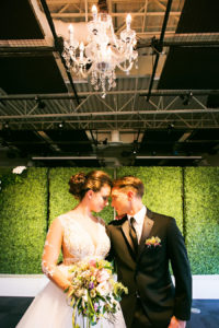 Modern Greenery Inspired Indoor Garden Wedding Ceremony | Greenery Hedge Wall Ceremony Backdrop with Clear Ghost Chairs and Hanging Chandelier | Tampa Bay Bridal Shop Isabel O'Neil Bridal | Rental and Decor Company A Chair Affair | Wedding Photographer Limelight Photography | Downtown Tampa Venue Glazer's Children Museum | Lighting Nature Coast Entertainment Services