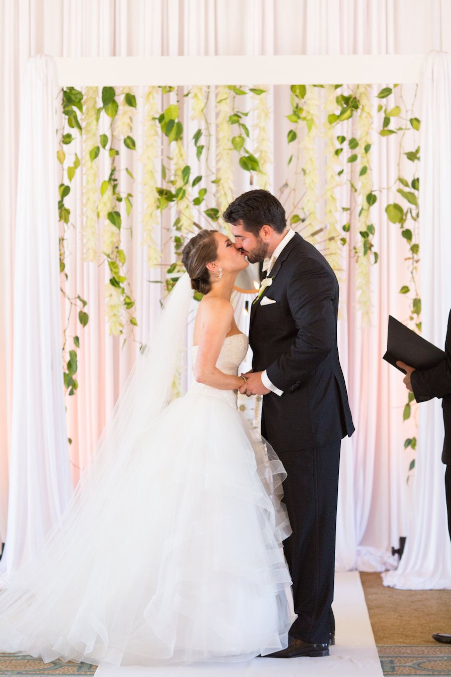 Alessandra Alessi Bridal Wedding Ceremony Portrait Bride and Groom Kiss | Elegant Wedding Ceremony Decor Altar White Draped Backdrop with Hanging Flowers, Greenery and Gold Mirror | Tampa Bay Wedding Photographer Brandi Image Photography | Planner Parties a la Carte