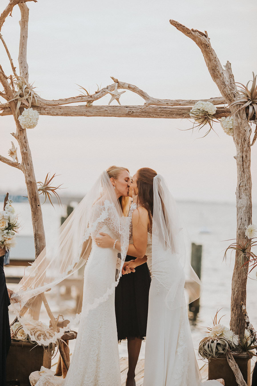 Florida Same Sex Gay Waterfront Wedding Ceremony Sunset Portrait of Brides in Ivory Wedding Dress First Kiss | Tampa Wedding Photographer Rad Red Creative