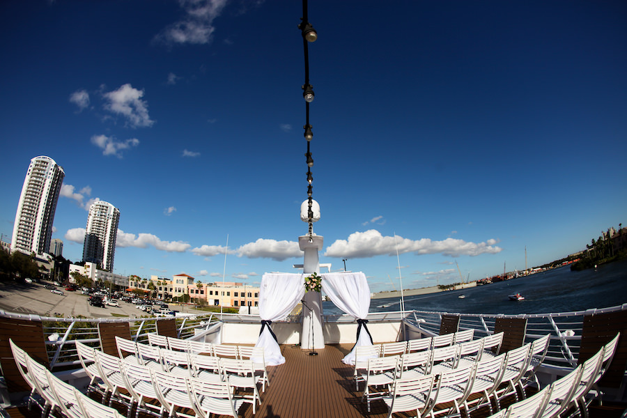 Tampa Boat Wedding Ceremony Venue with White Resin Folding Chairs and White Wedding Arch with Navy Ribbon on the Yacht Starship II