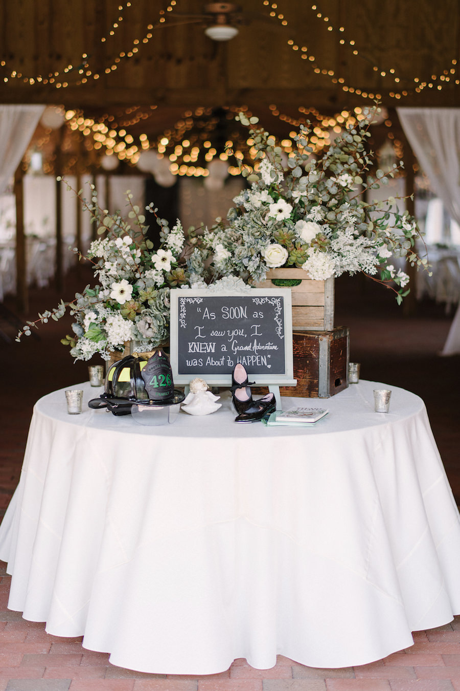 Rustic Wedding Guest Book Table With Ivory Flowers, Eucalyptus, and Dusty Miller Greenery with Chalk Sign and Twinkle Lights at Tampa Bay Wedding Venue Cross Creek Ranch