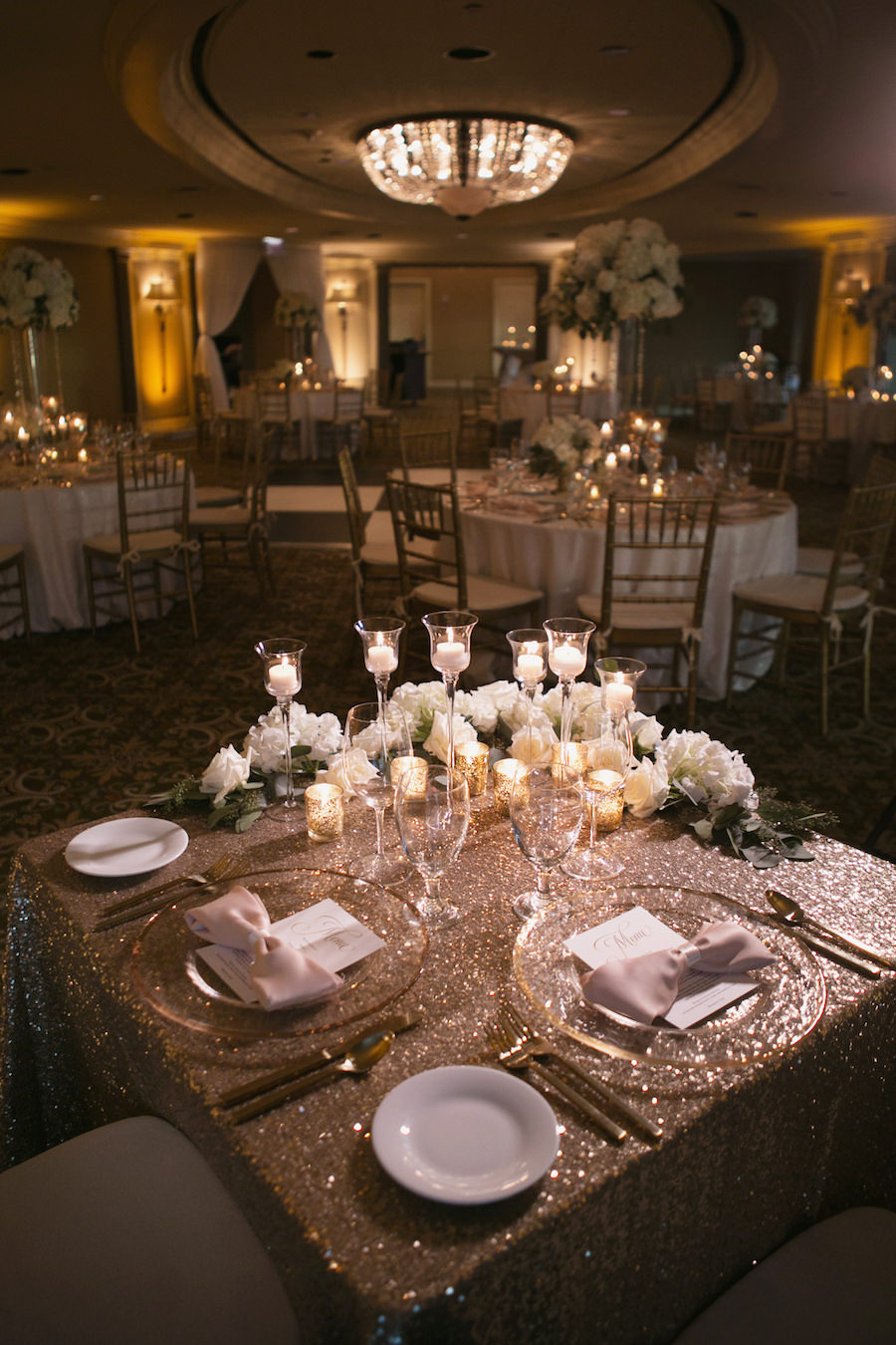 Gold and Ivory Wedding Sweetheart Table with Gold Glitter Linens and White Roses with Gold Mercury Tea Light Candles and Medium Tea Light White Candles in Glass Candle Holders with Gold Chiavari Chairs | Tampa Wedding Rentals A Chair Affair | Tampa Wedding Linens Gabro Event Services | Wedding Venue The Tampa Club | Wedding Photographer Carrie Wildes Photography | Tampa Bay Wedding Florist Northside Florist