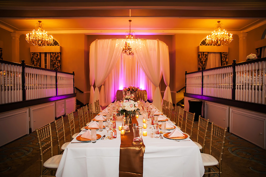 Long Wedding Feasting Tables with Ivory Linens and Gold Satin Table Runners with Gold Chiavari Chairs and Pink Uplighting | St Petersburg Wedding Venue The Don Cesar | St Petersburg Wedding Photographer Limelight Photography